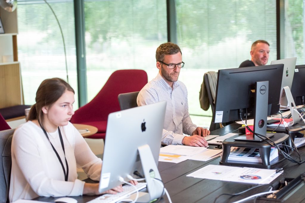 lady-and-men-working-in-office Team working behind desk and computers